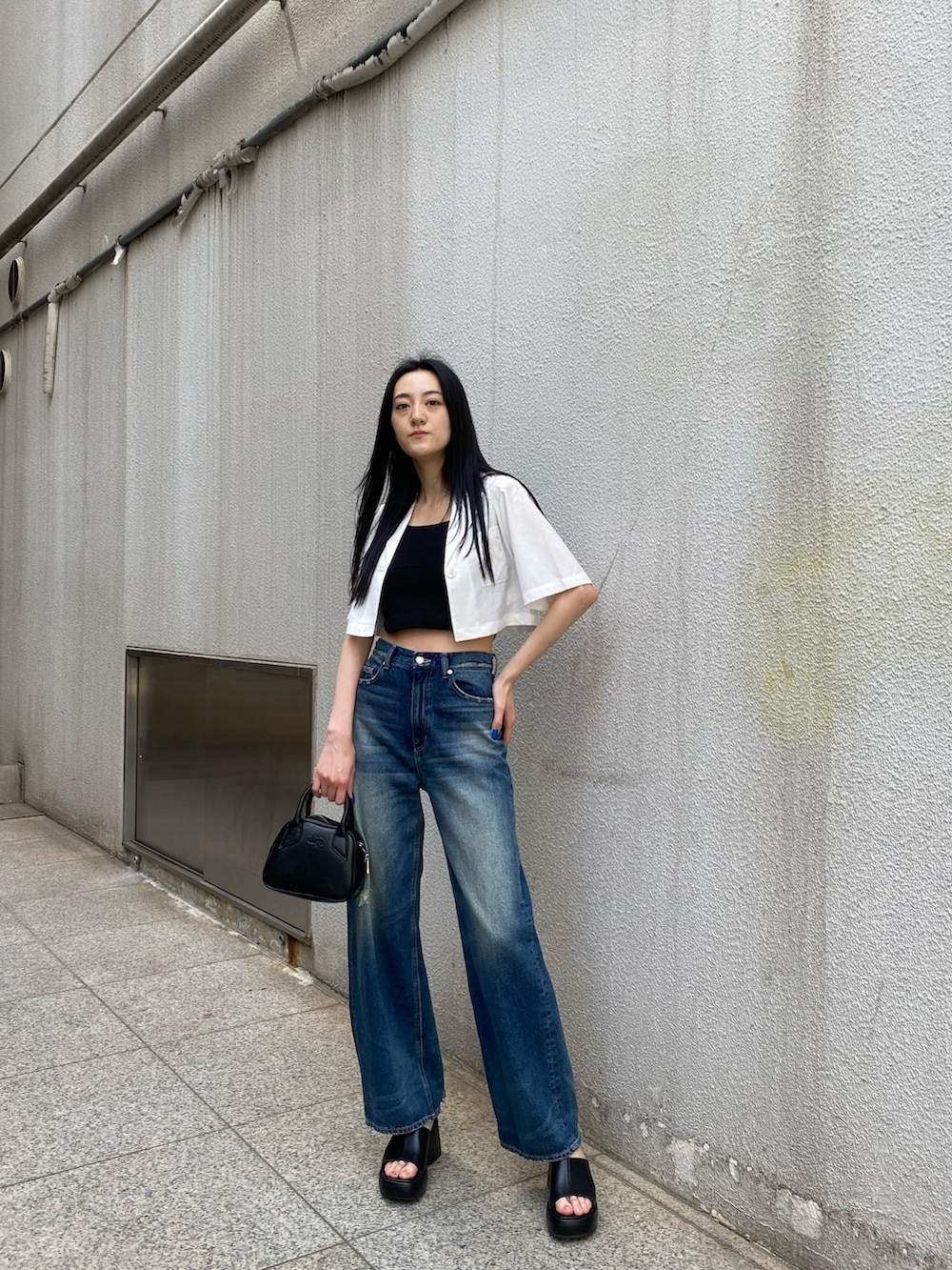 ブルー系のデニムパンツ、ブラック系のニット/セーター、ホワイト系のシャツ/ブラウスを着用したレディースの春コーディネートの2枚目の写真