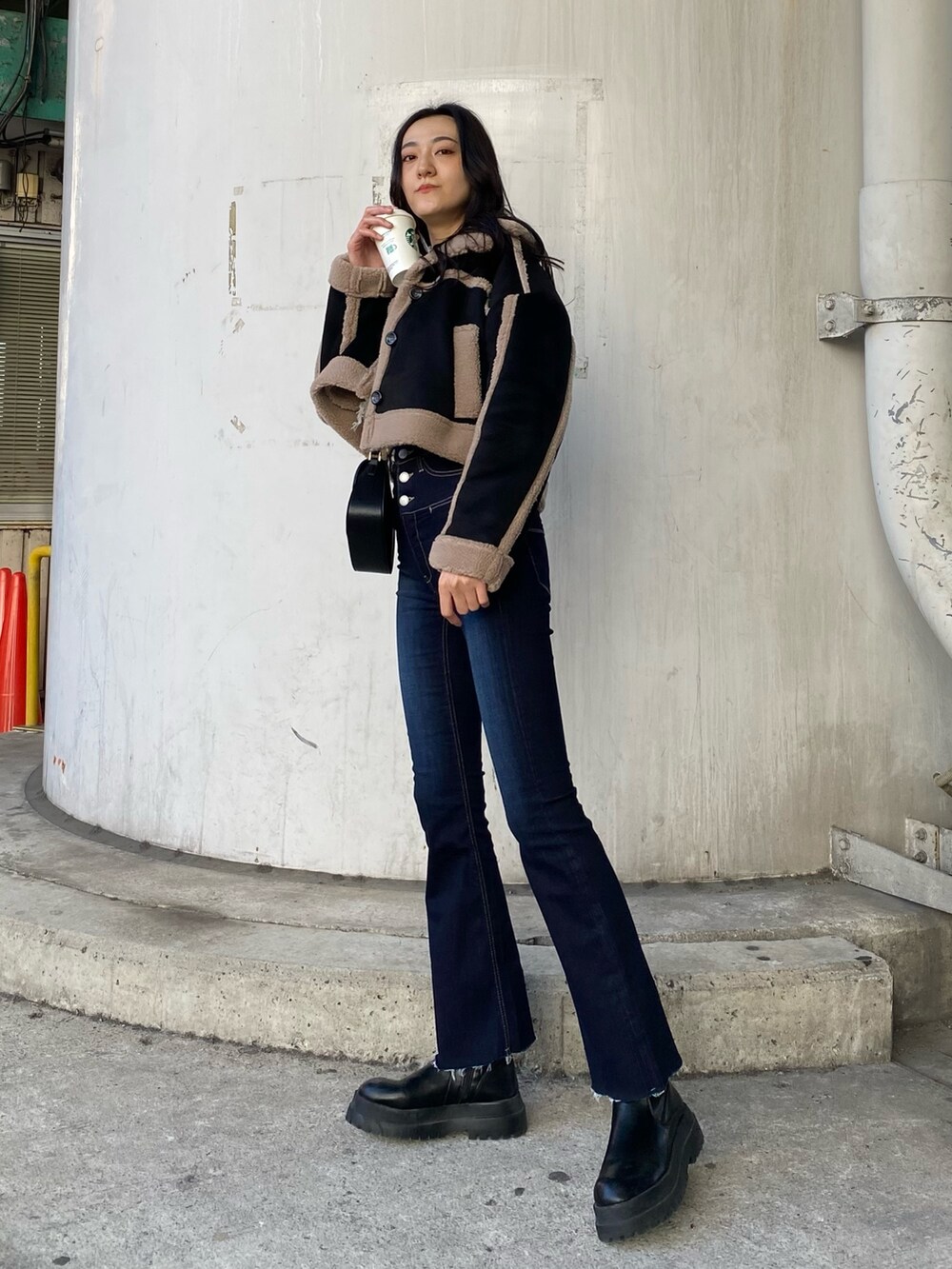 ブルー系のデニムパンツ、ブラック系のムートンコート、ホワイト系のニット/セーターを着用したレディースの秋コーディネートの4枚目の写真