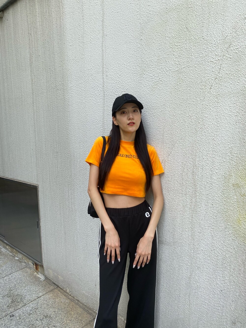 ブラック系のその他パンツ、ブラック系のハンドバッグ、オレンジ系のTシャツ/カットソーを着用したレディースの夏コーディネートの6枚目の写真