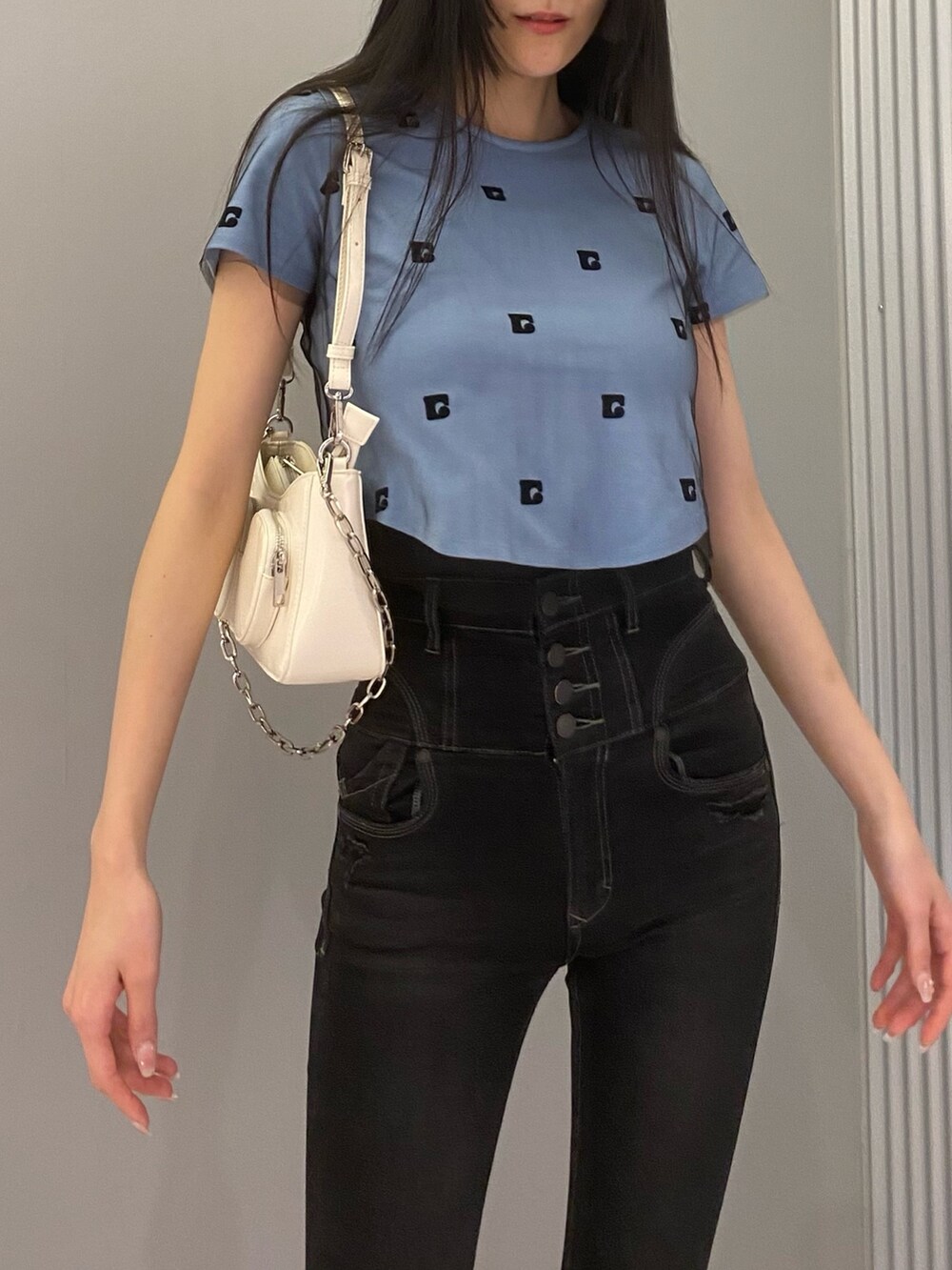 ブラック系のデニムパンツ、ブルー系のTシャツ/カットソー、ホワイト系のショルダーバッグを着用したレディースの春コーディネートの3枚目の写真