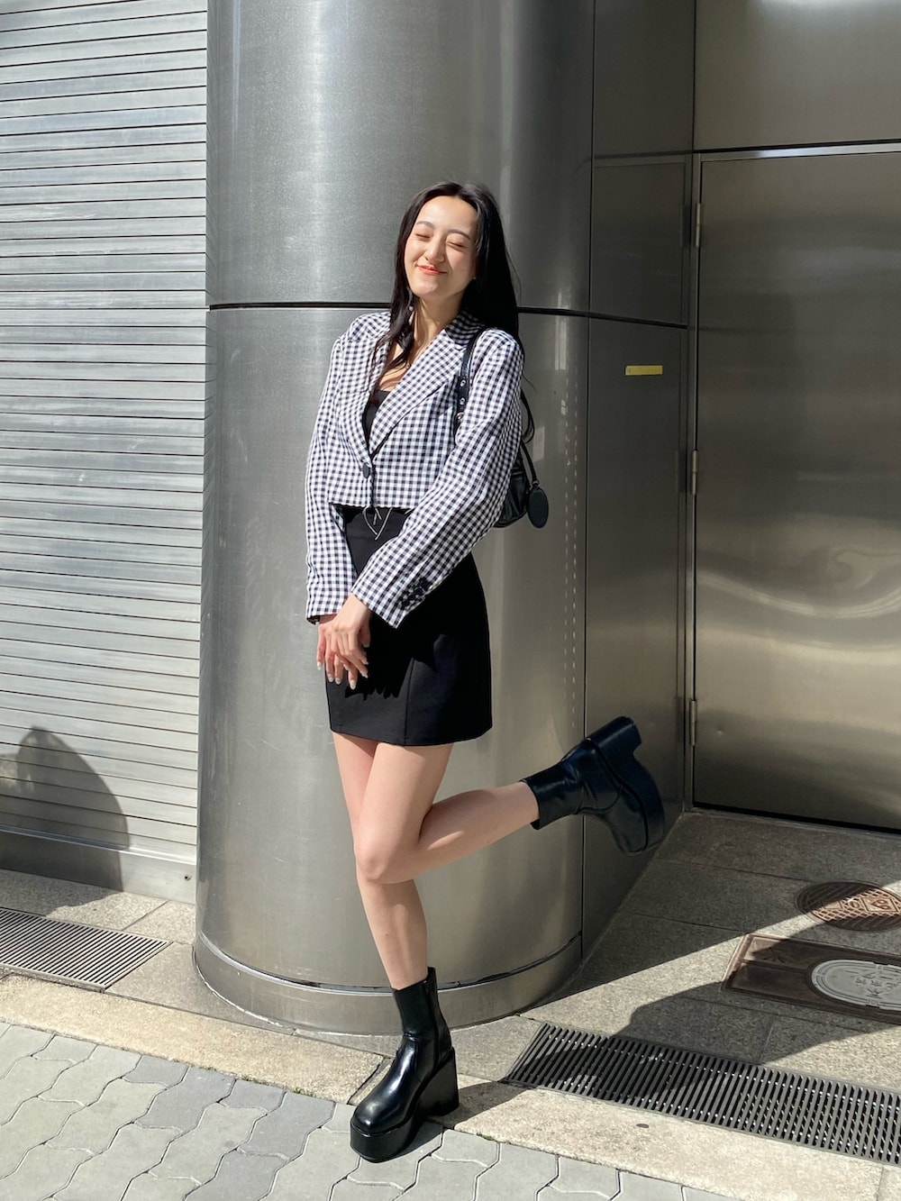 ブラック系のブーツ、ブラック系のスカート、ブラック系のハンドバッグを着用したレディースの春コーディネートの2枚目の写真