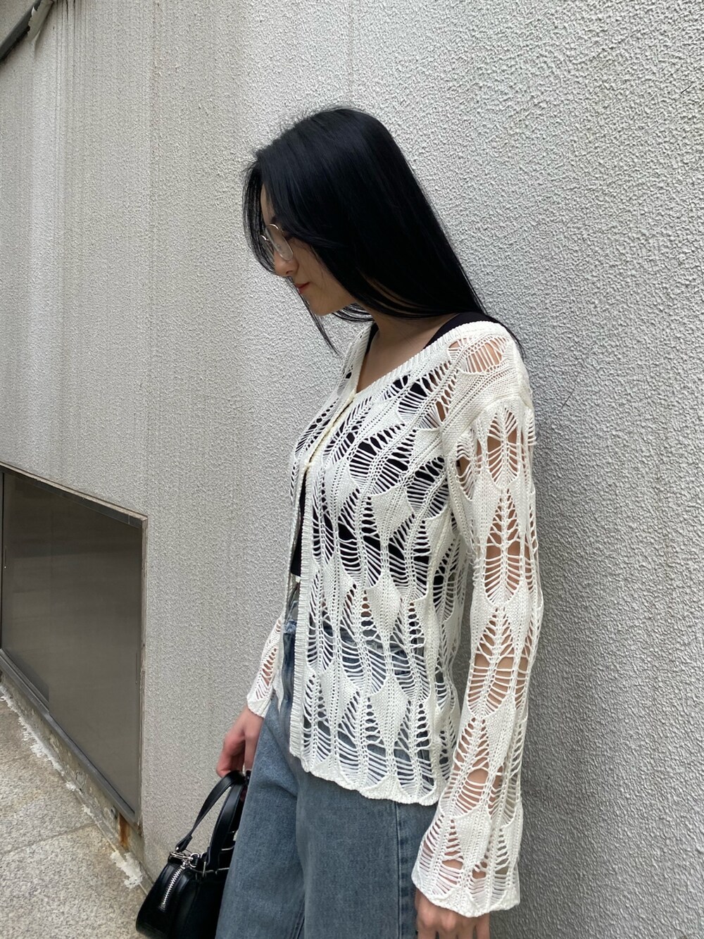 ブラック系のハンドバッグ、ブラック系のサンダル、ブルー系のデニムパンツを着用したレディースの春コーディネートの8枚目の写真