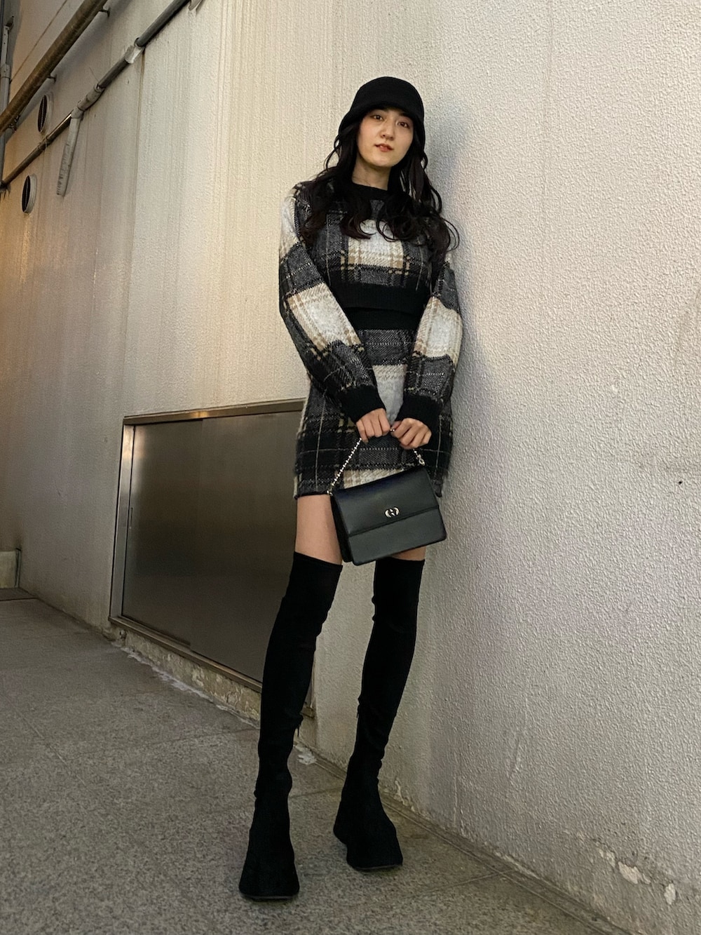 ブラック系のスカート、ブラック系のニット/セーター、ブラック系のブーツを着用したレディースの冬コーディネートの2枚目の写真