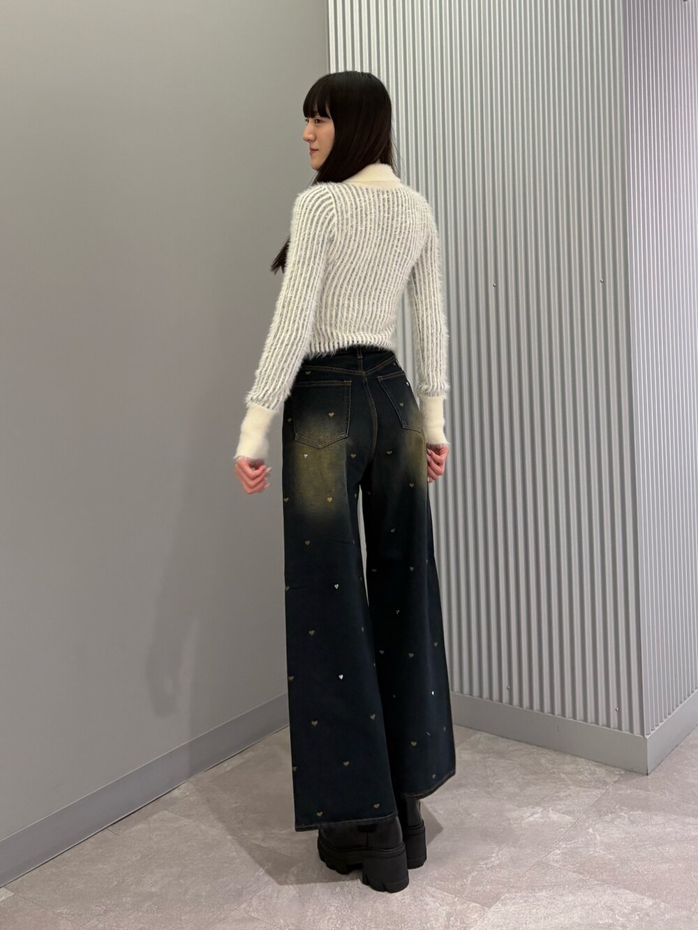 ブルー系のデニムパンツ、ホワイト系のニット/セーター、ブラック系のブーツを着用したレディースの秋コーディネートの3枚目の写真