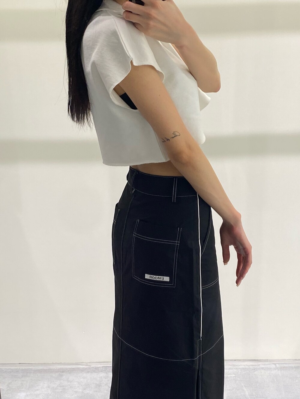 ブラック系のスカート、ホワイト系のTシャツ/カットソー、ブラック系のサンダルを着用したレディースの夏コーディネートの6枚目の写真