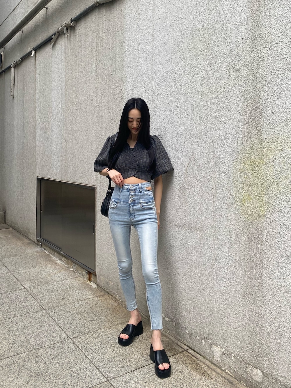 ブラック系のショルダーバッグ、ブラック系のTシャツ/カットソー、ブルー系のデニムパンツを着用したレディースの夏コーディネートの3枚目の写真