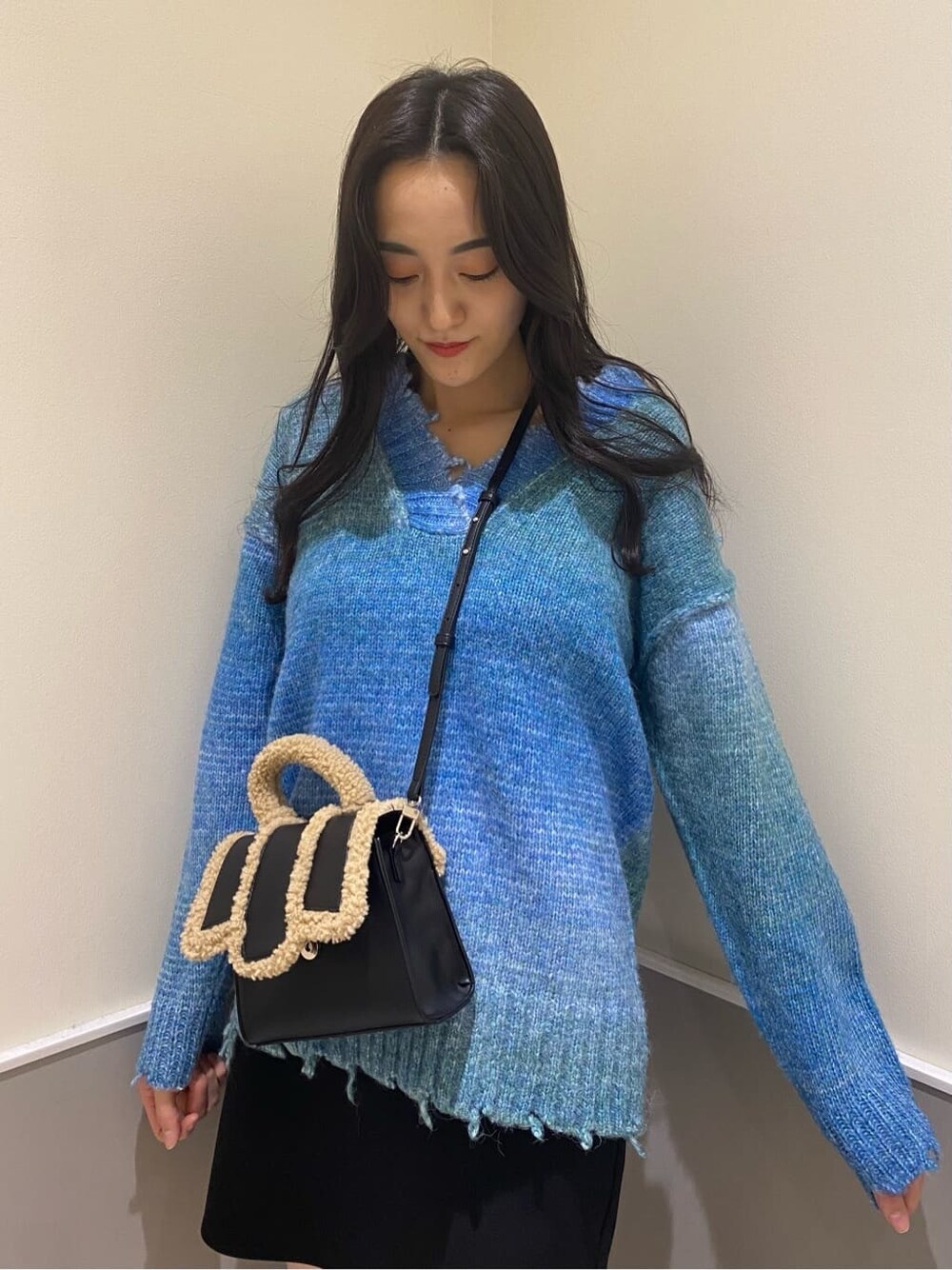 ブラック系のブーツ、ブラック系のスカート、ブルー系のニット/セーターを着用したレディースの秋コーディネートの6枚目の写真