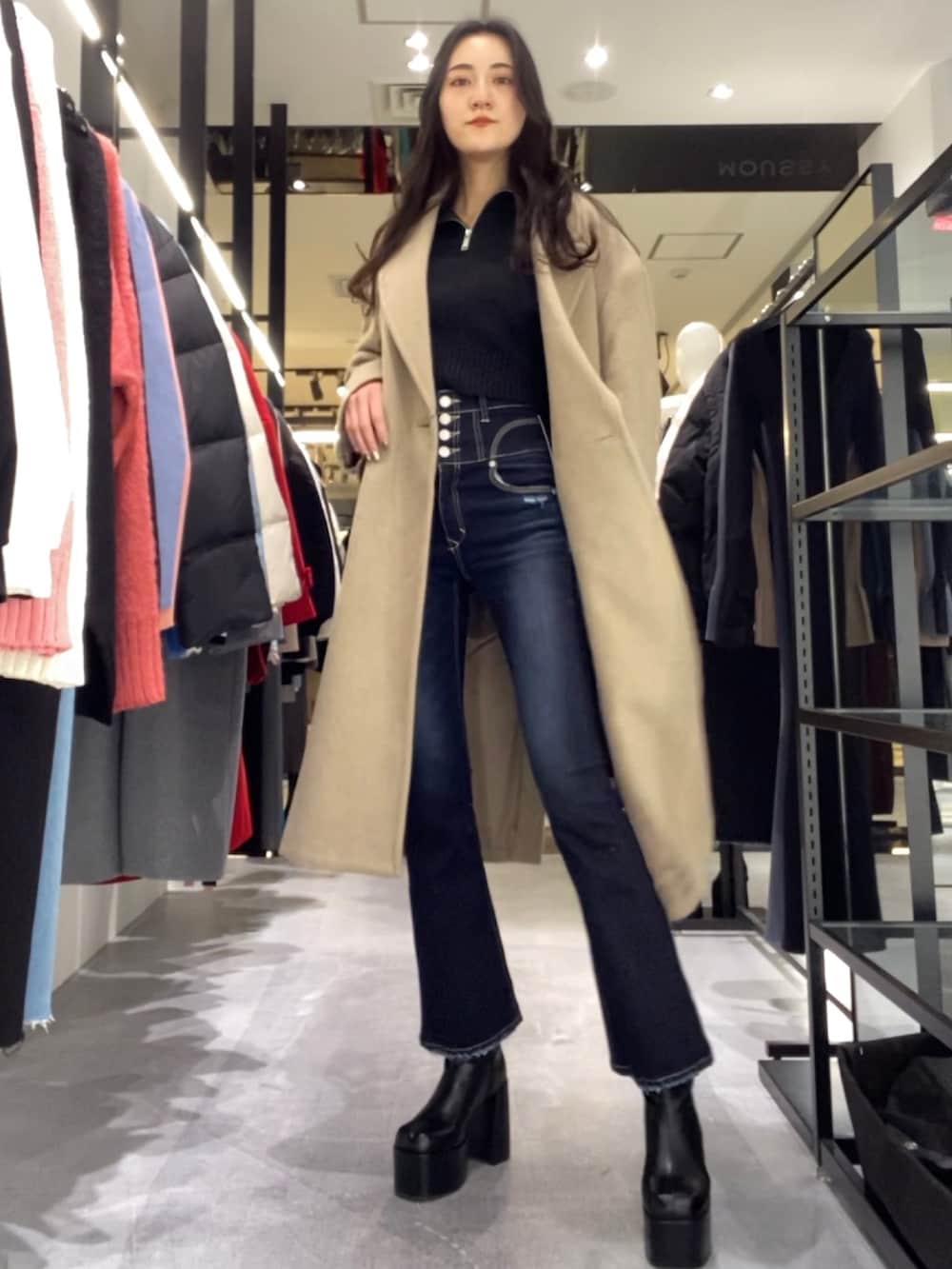 ベージュ系のチェスターコート、ブラック系のニット/セーター、ブルー系のデニムパンツを着用したレディースの冬コーディネートの3枚目の写真