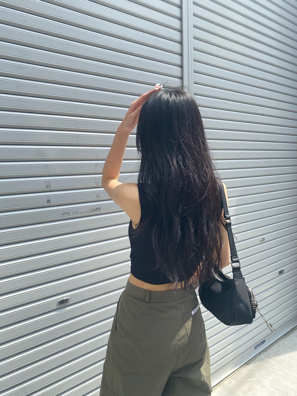 ベージュ系のカーゴパンツ、ブラック系のタンクトップ、ブラック系のハンドバッグを着用したレディースの夏コーディネートの5枚目の写真