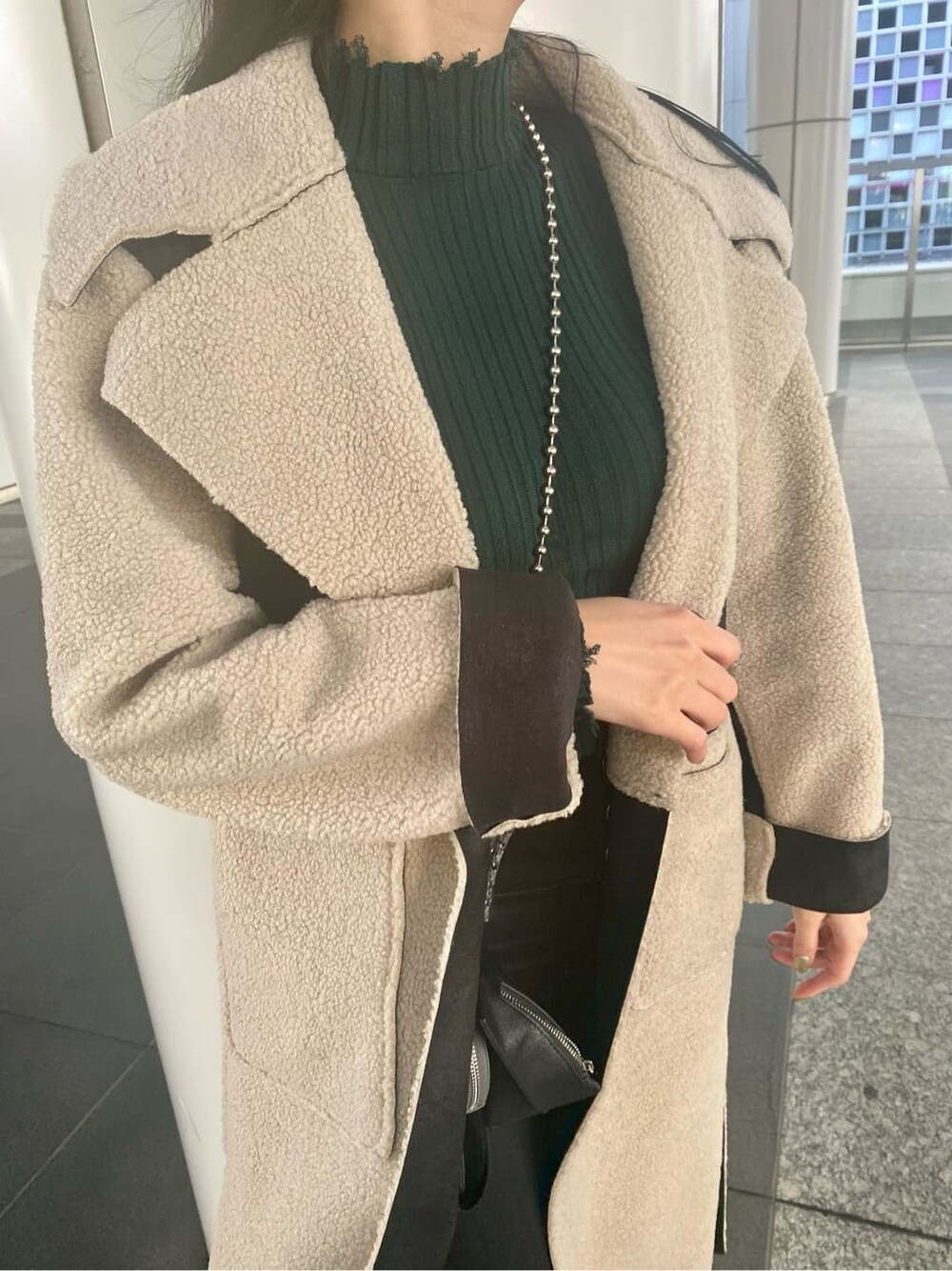 ブラック系のデニムパンツ、ブラック系のムートンコート、ブラック系のショルダーバッグを着用したレディースの冬コーディネートの6枚目の写真