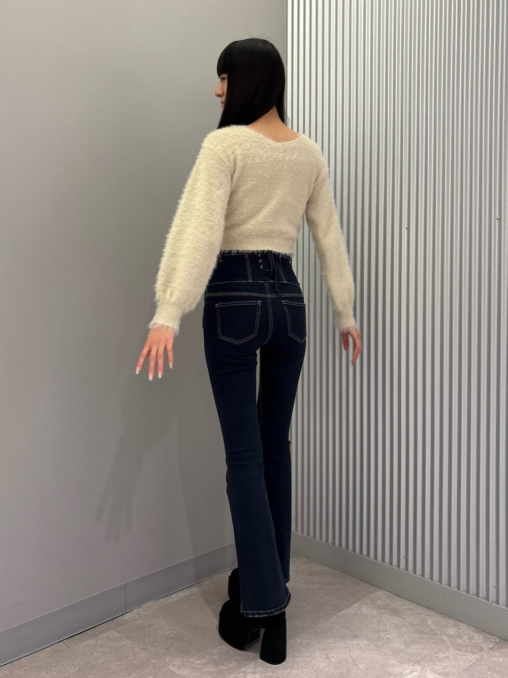 ブルー系のデニムパンツ、ブラック系のキャミソール、ホワイト系のニット/セーターを着用したレディースの秋コーディネートの4枚目の写真