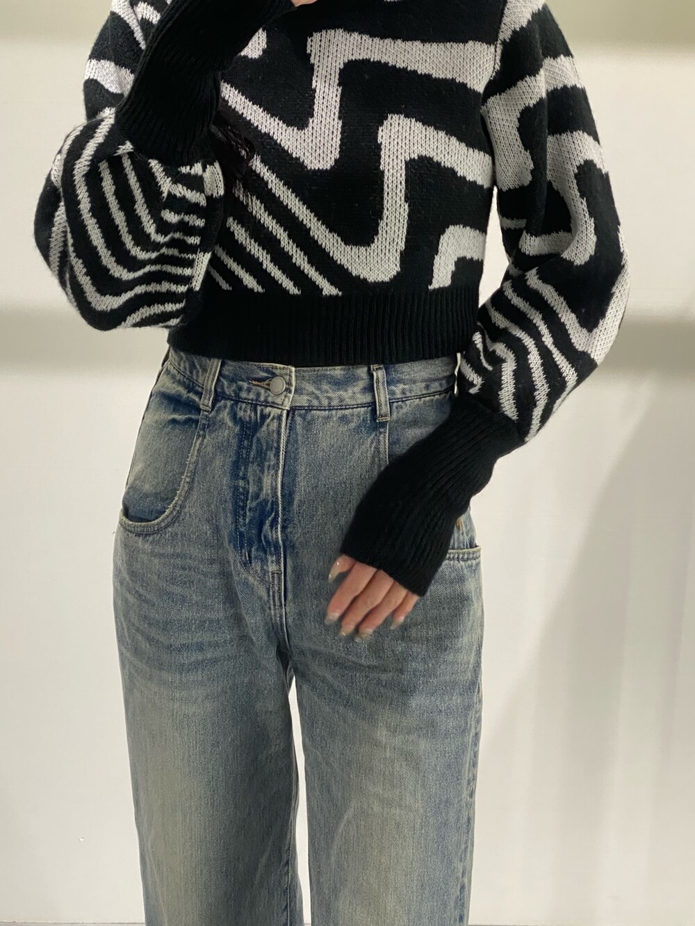 ブルー系のデニムパンツ、ブラック系のニット/セーター、ブラック系のブーツを着用したレディースの冬コーディネートの3枚目の写真