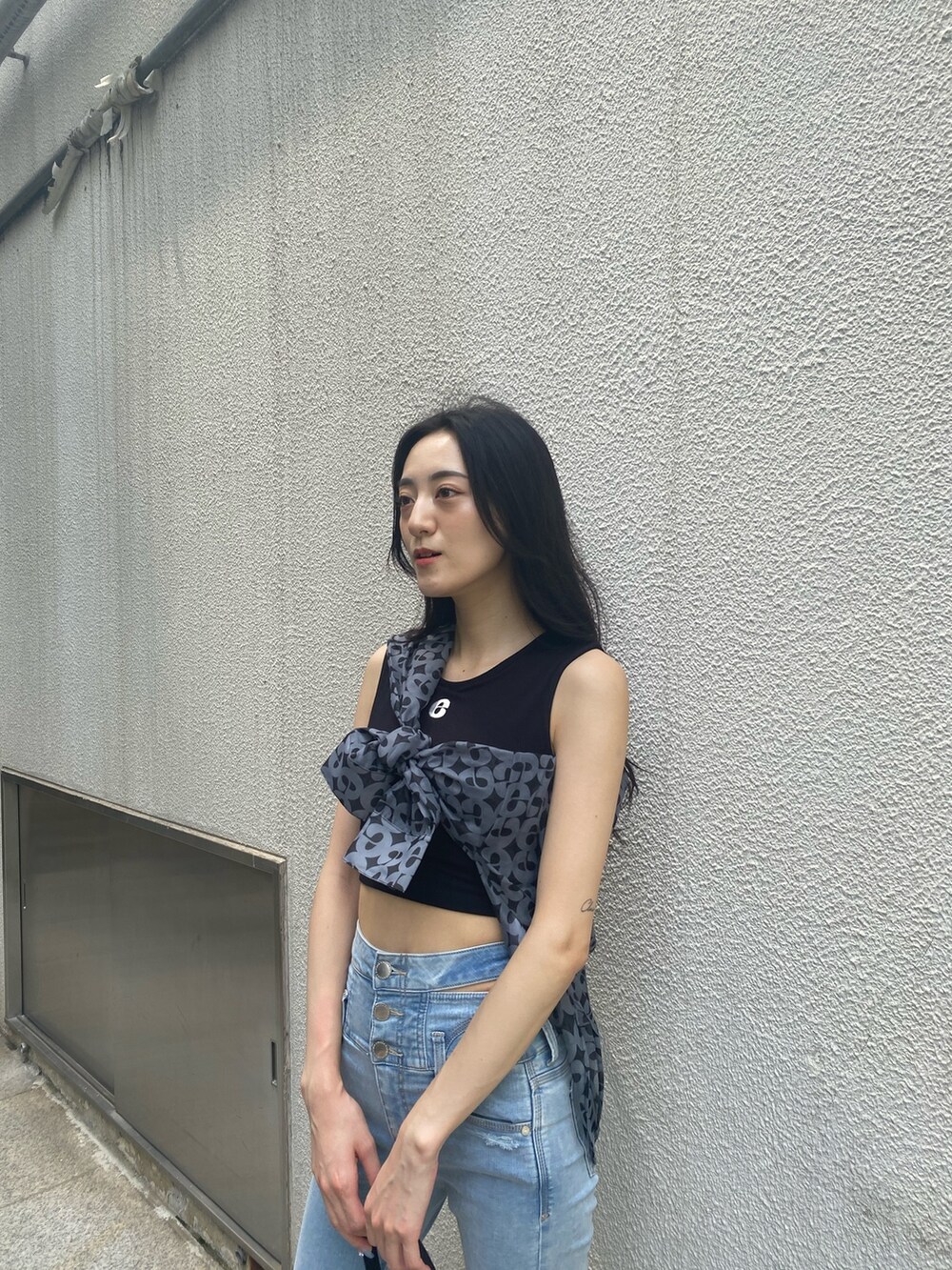 ブルー系のデニムパンツ、ブラック系のハンドバッグ、ブラック系のサンダルを着用したレディースの夏コーディネートの7枚目の写真