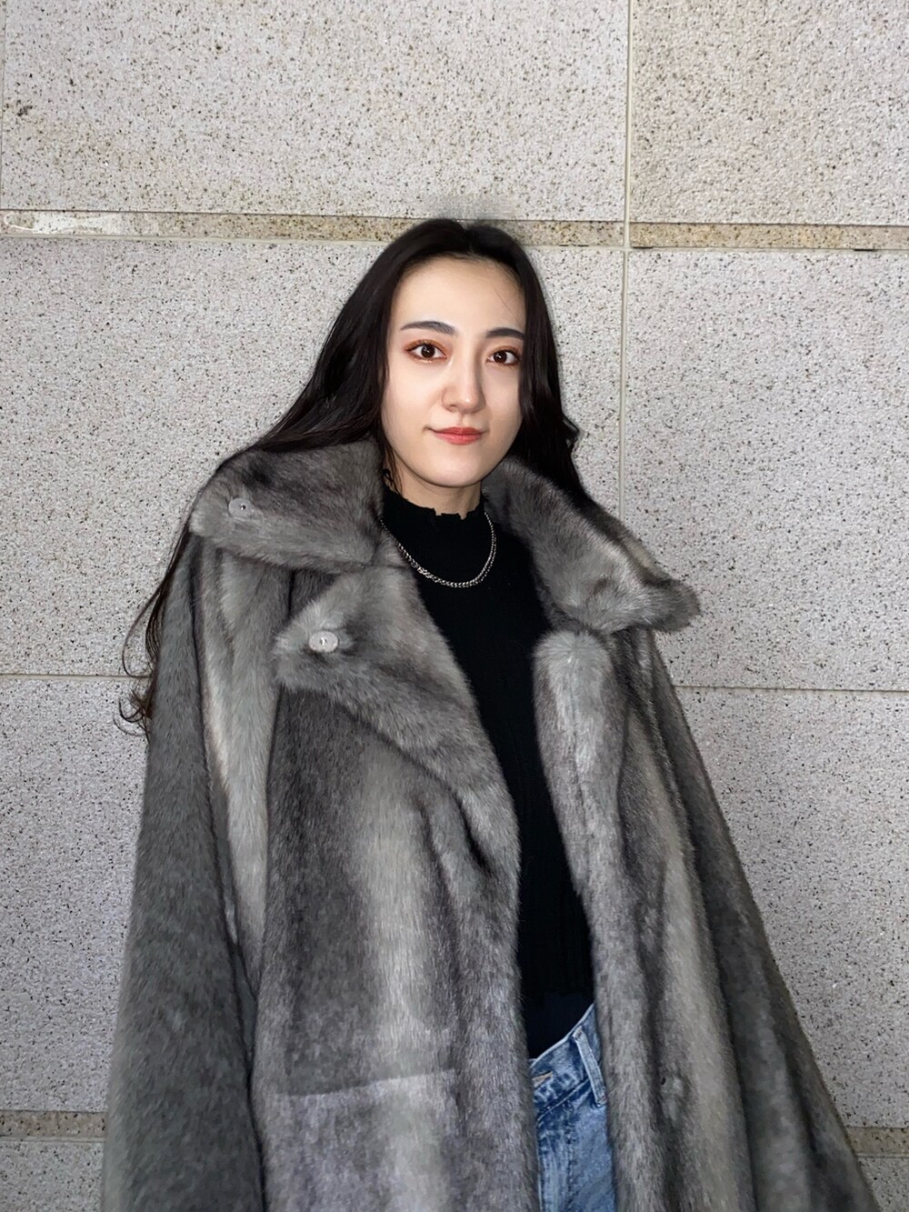 ブラック系のニット/セーター、グレー系のその他アウター、ブルー系のデニムパンツを着用したレディースの冬コーディネートの6枚目の写真