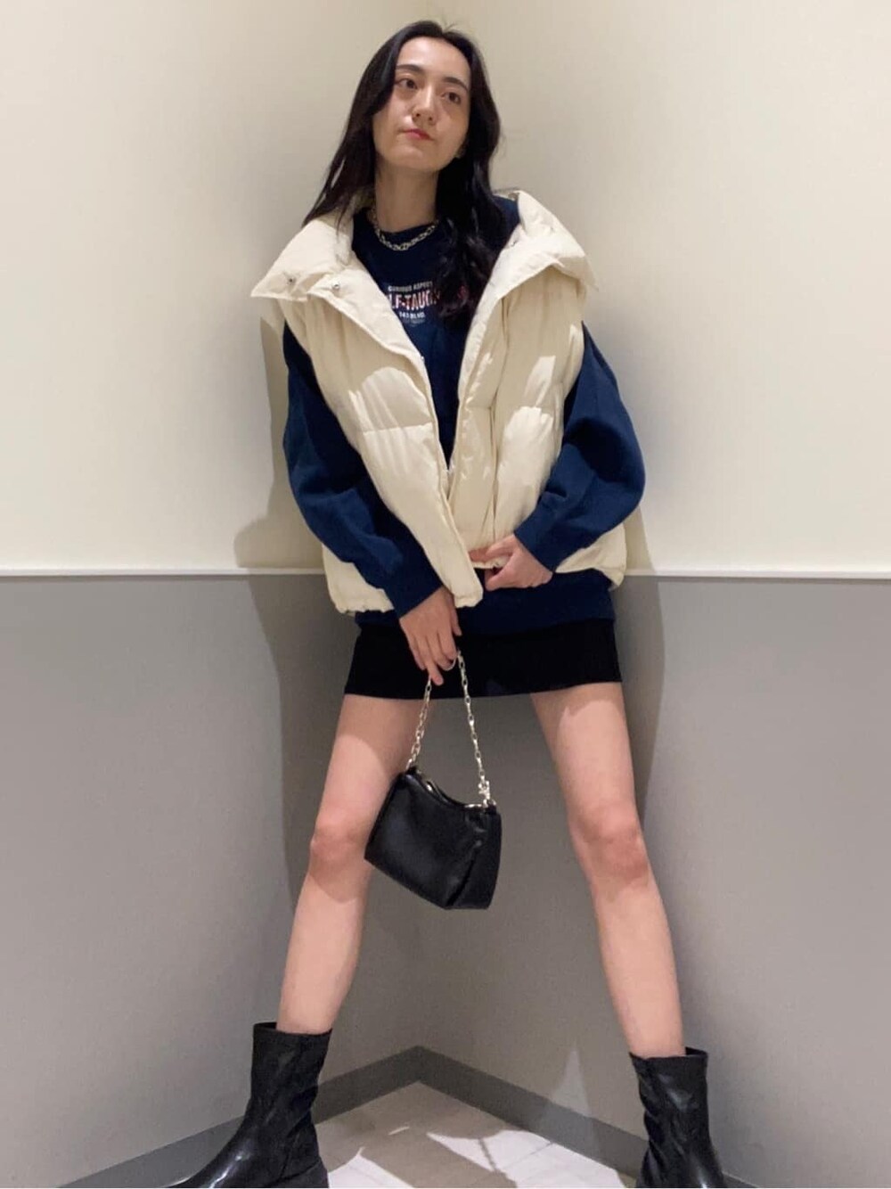 ブラック系のスカート、ホワイト系のダウンベスト、ブルー系のスウェットを着用したレディースの秋コーディネートの3枚目の写真