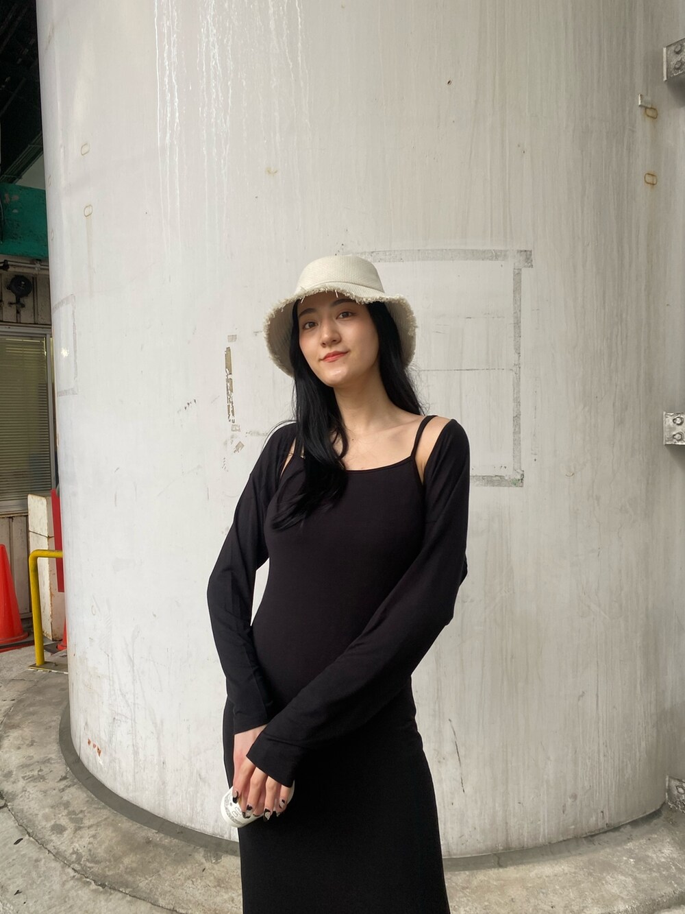 ブラック系のワンピース、ブラック系のサンダル、ホワイト系のハットを着用したレディースの春コーディネートの6枚目の写真