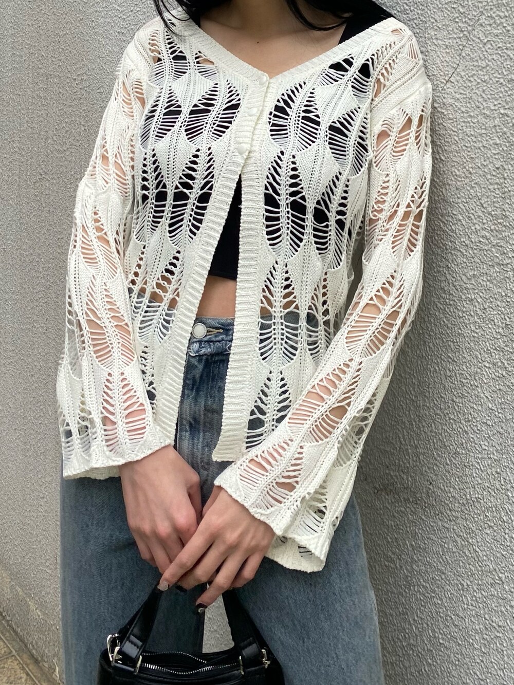 ブラック系のハンドバッグ、ブラック系のサンダル、ブルー系のデニムパンツを着用したレディースの春コーディネートの5枚目の写真