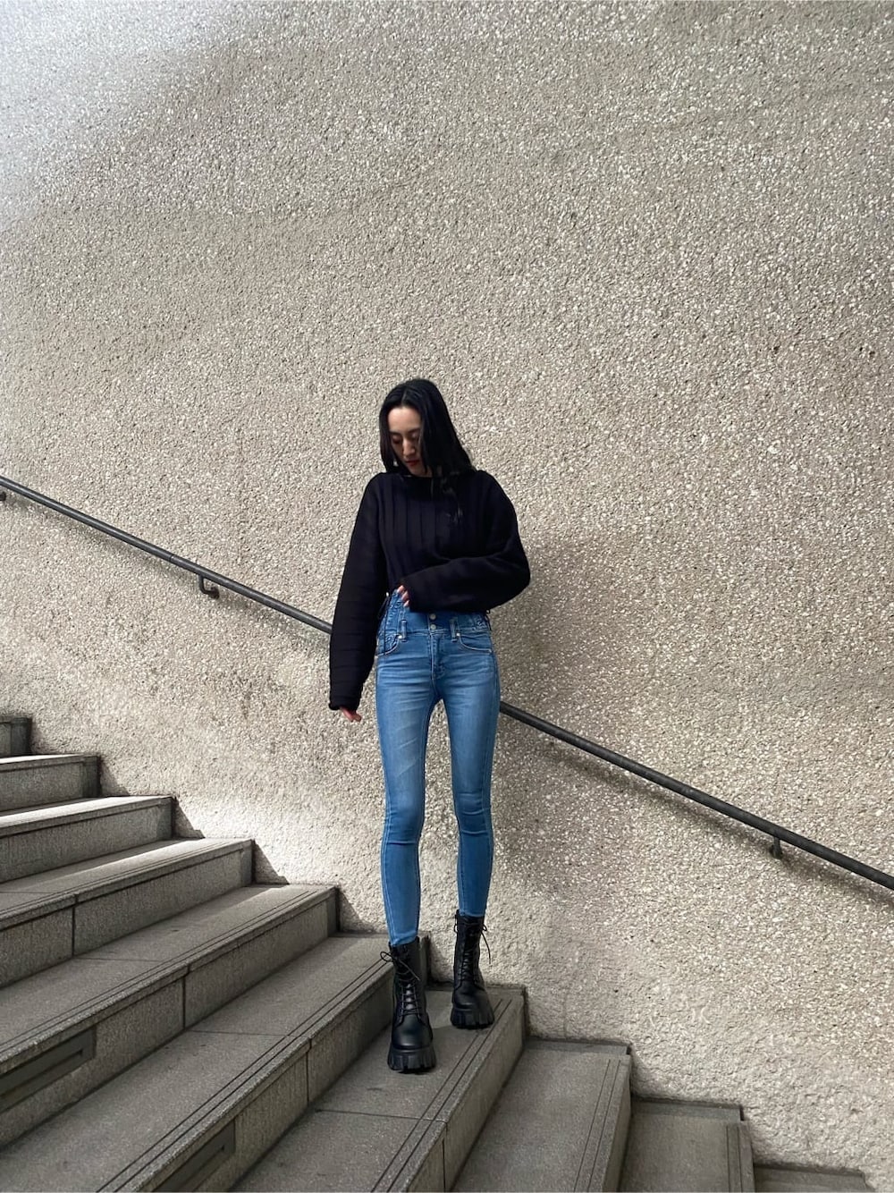 ブルー系のデニムパンツ、ブラック系のニット/セーター、ブラック系のブーツを着用したレディースの冬コーディネートの2枚目の写真