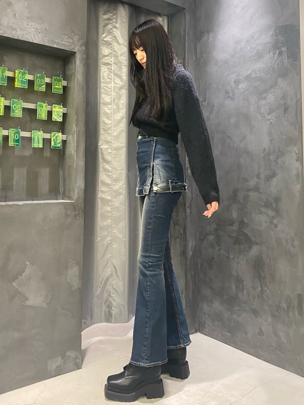 ブルー系のデニムパンツ、ブラック系のニット/セーター、ブラック系のブーツを着用したレディースの秋コーディネートの2枚目の写真