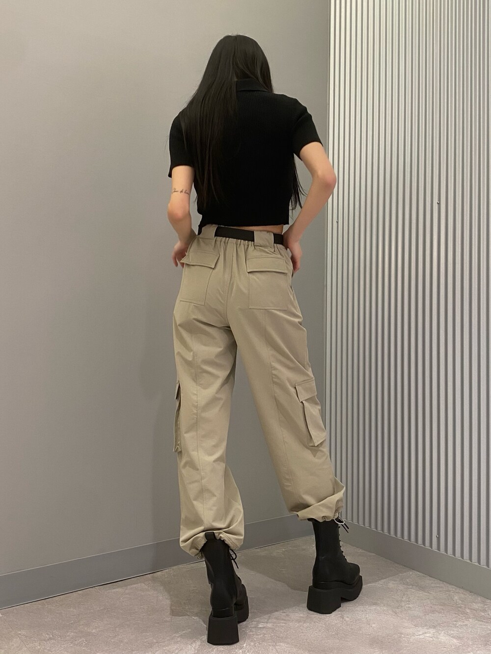ベージュ系のカーゴパンツ、ブラック系のニット/セーター、ブラック系のブーツを着用したレディースの春コーディネートの4枚目の写真