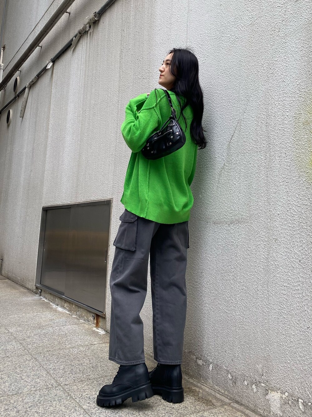 グリーン系のカーディガン/ボレロ、ホワイト系のキャミソール、ブラック系のデニムパンツを着用したレディースの春コーディネートの3枚目の写真