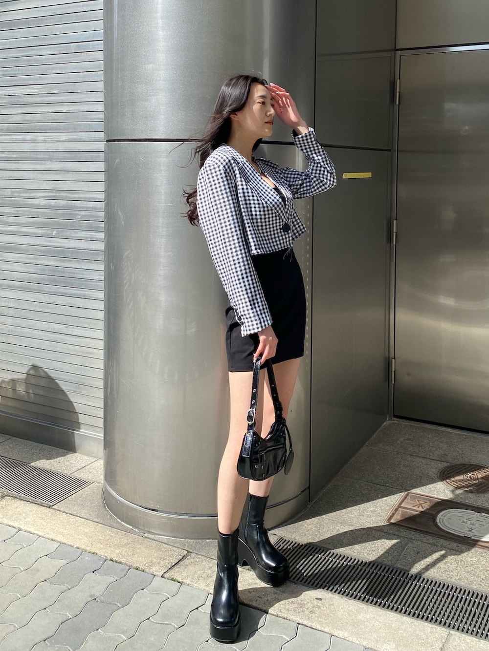 ブラック系のブーツ、ブラック系のスカート、ブラック系のハンドバッグを着用したレディースの春コーディネートの3枚目の写真