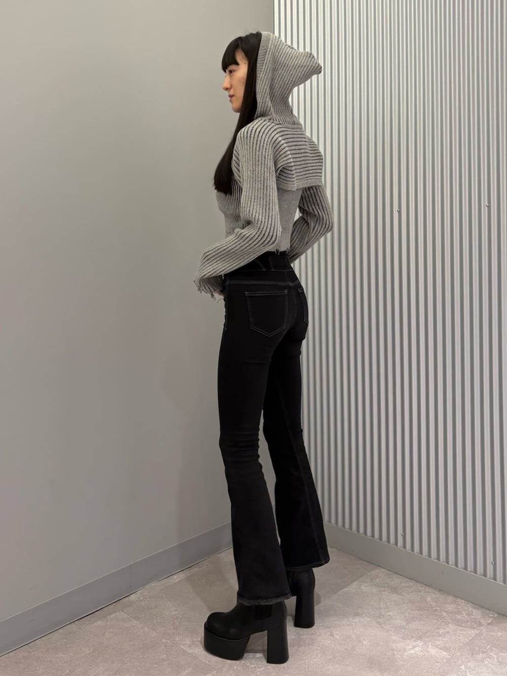 ブラック系のデニムパンツ、ブラック系のブーツ、グレー系のニット/セーターを着用したレディースの秋コーディネートの3枚目の写真