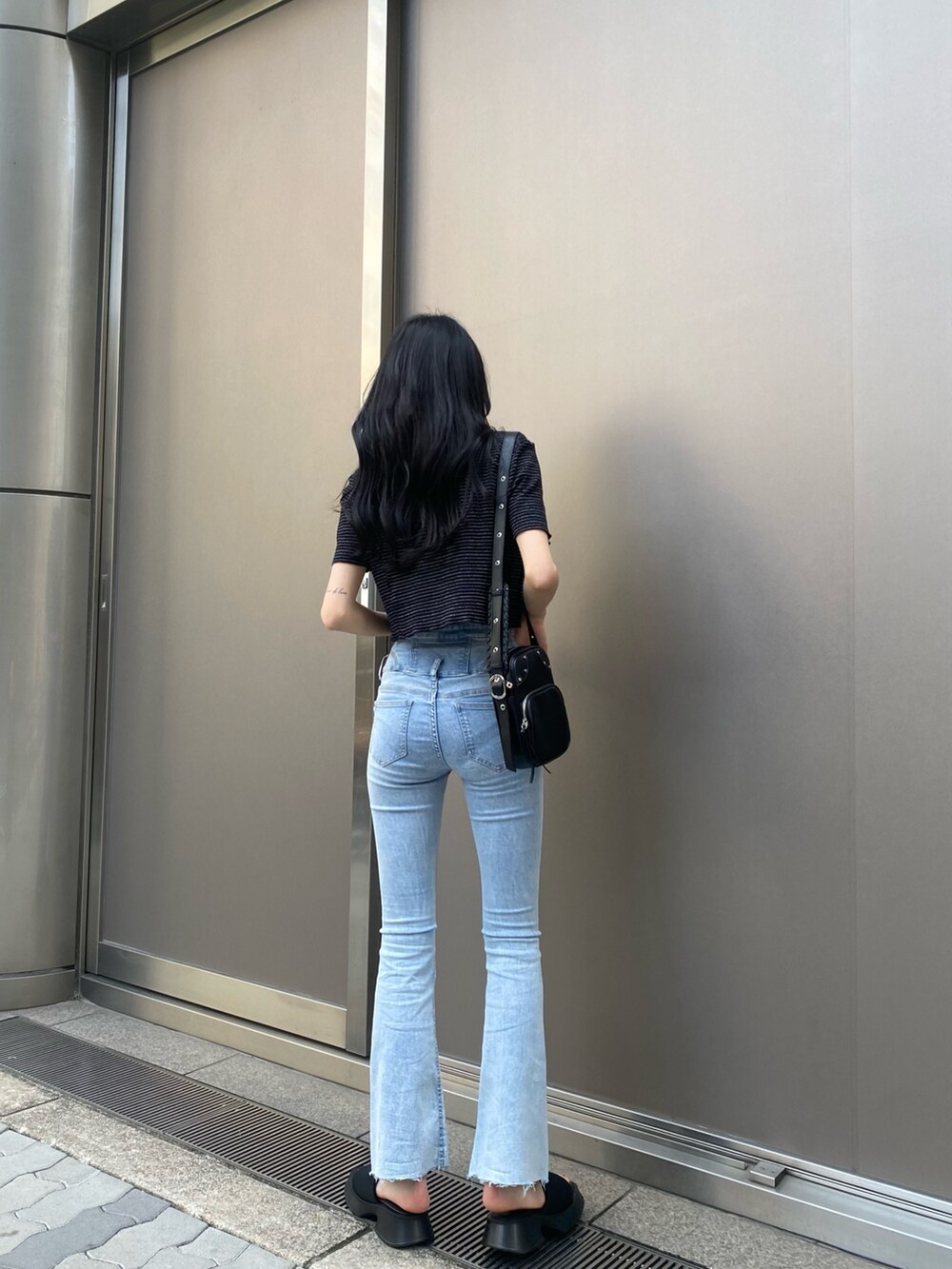 ブラック系のアンサンブル、ブルー系のデニムパンツ、ブラック系のサンダルを着用したレディースの春コーディネートの3枚目の写真