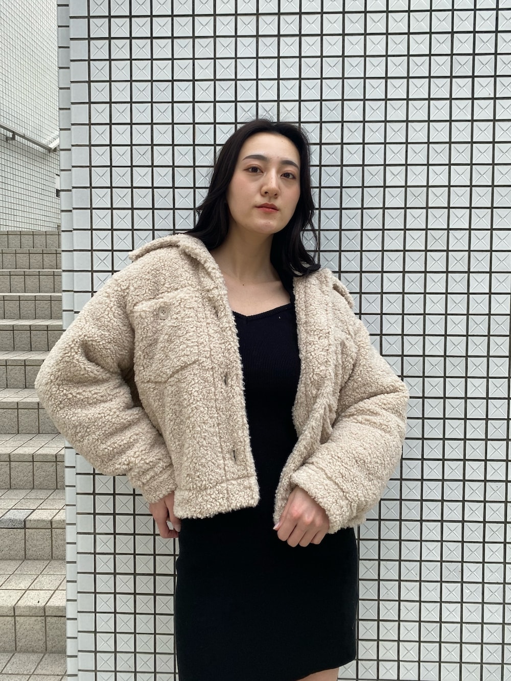 ブラック系のワンピース、ホワイト系のブルゾン、ブラック系のブーツを着用したレディースの冬コーディネートの5枚目の写真