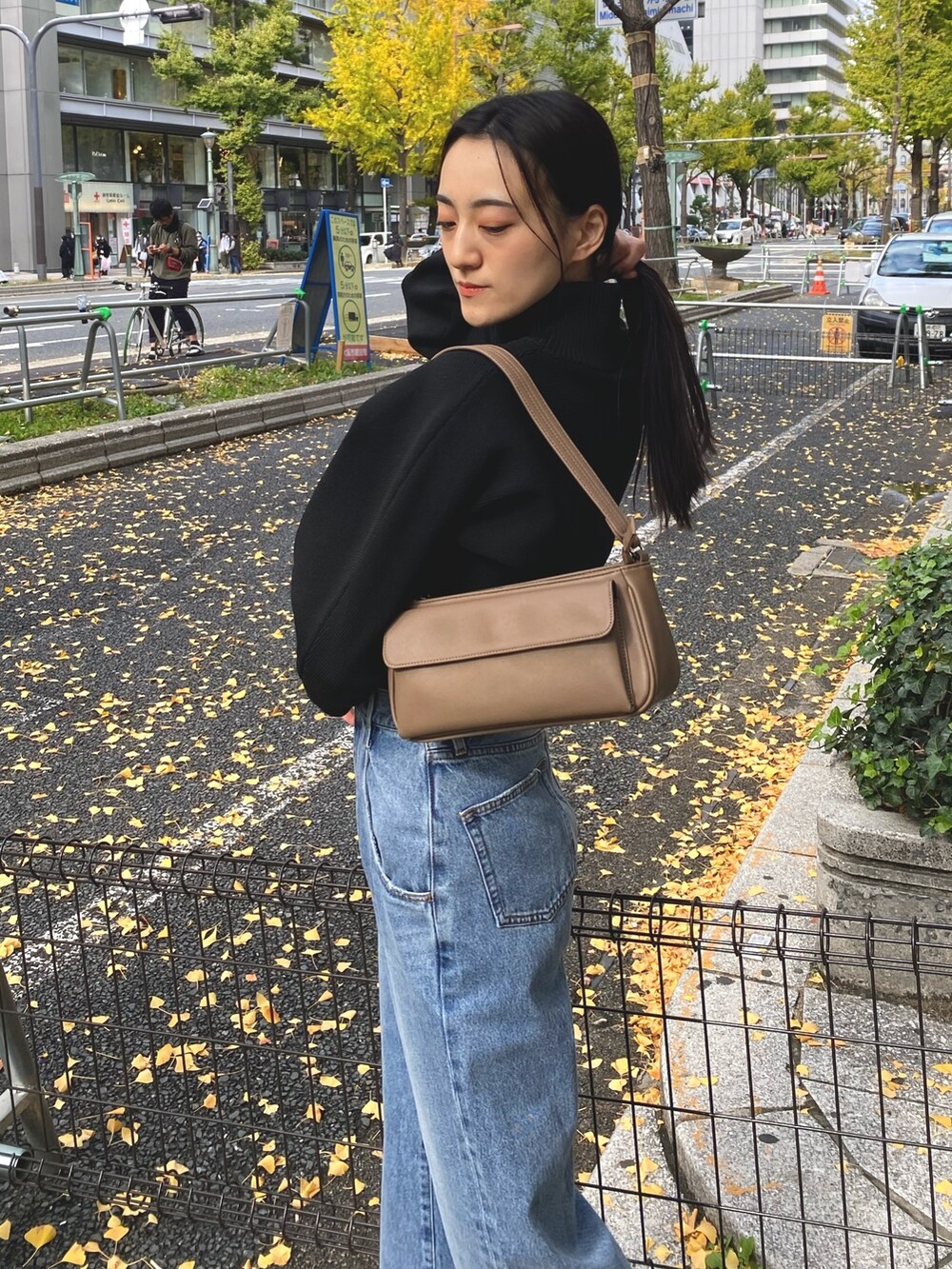 ブルー系のデニムパンツ、ブラック系のブーツ、ブラウン系のハンドバッグを着用したレディースの秋コーディネートの6枚目の写真