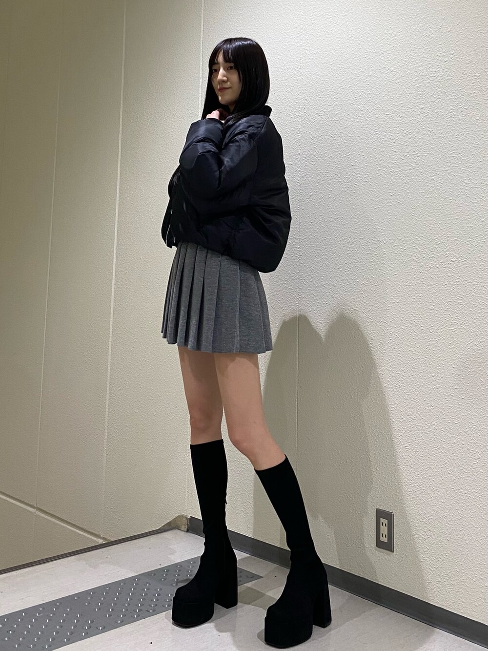 グレー系のスカート、ブラック系のブルゾン、その他のブーツを着用したレディースの秋コーディネートの5枚目の写真