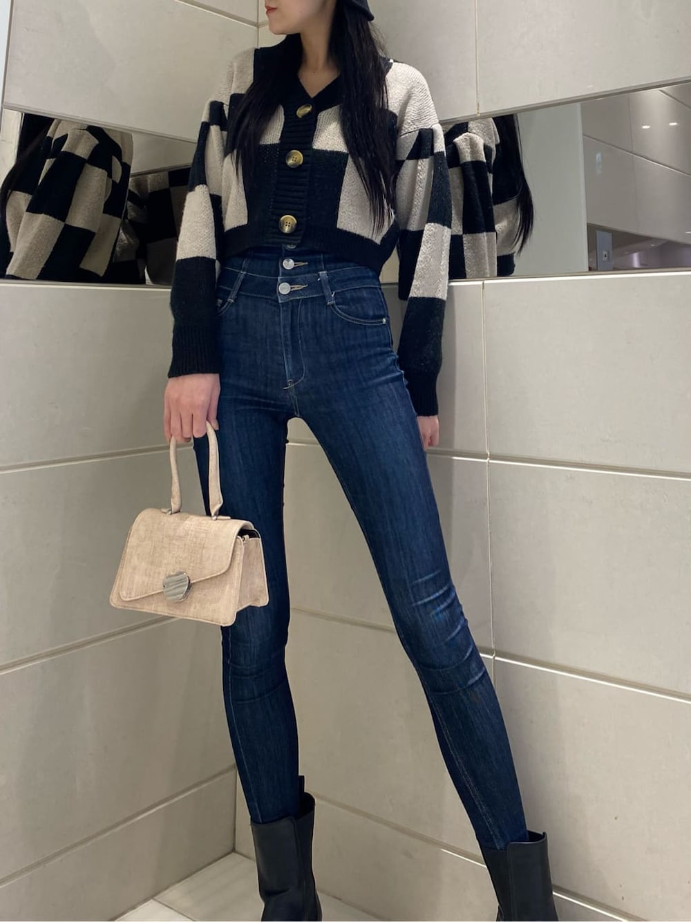 ブルー系のデニムパンツ、ブラック系のカーディガン/ボレロ、ベージュ系のハンドバッグを着用したレディースの冬コーディネートの2枚目の写真