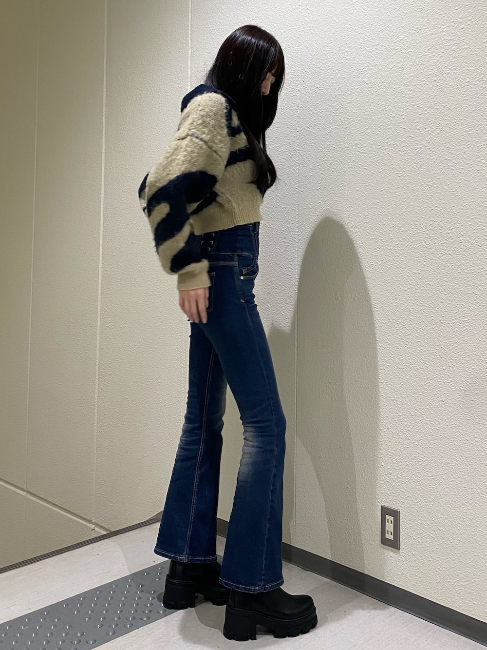 ブルー系のデニムパンツ、ブルー系のニット/セーター、ブラック系のブーツを着用したレディースの秋コーディネートの3枚目の写真