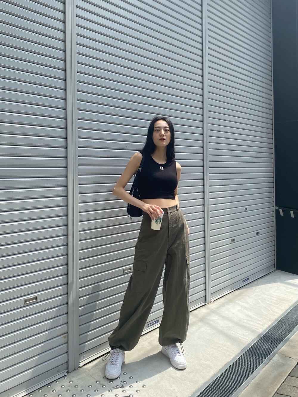 ベージュ系のカーゴパンツ、ブラック系のタンクトップ、ブラック系のハンドバッグを着用したレディースの夏コーディネートの2枚目の写真