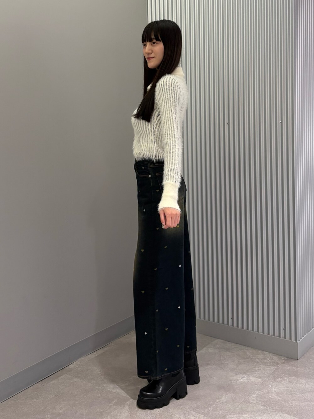 ブルー系のデニムパンツ、ホワイト系のニット/セーター、ブラック系のブーツを着用したレディースの秋コーディネートの2枚目の写真