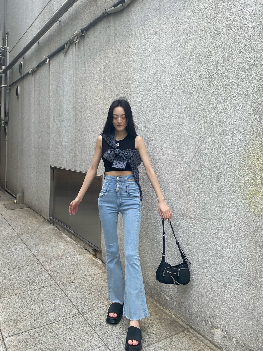 ブルー系のデニムパンツ、ブラック系のハンドバッグ、ブラック系のサンダルを着用したレディースの夏コーディネートの2枚目の写真