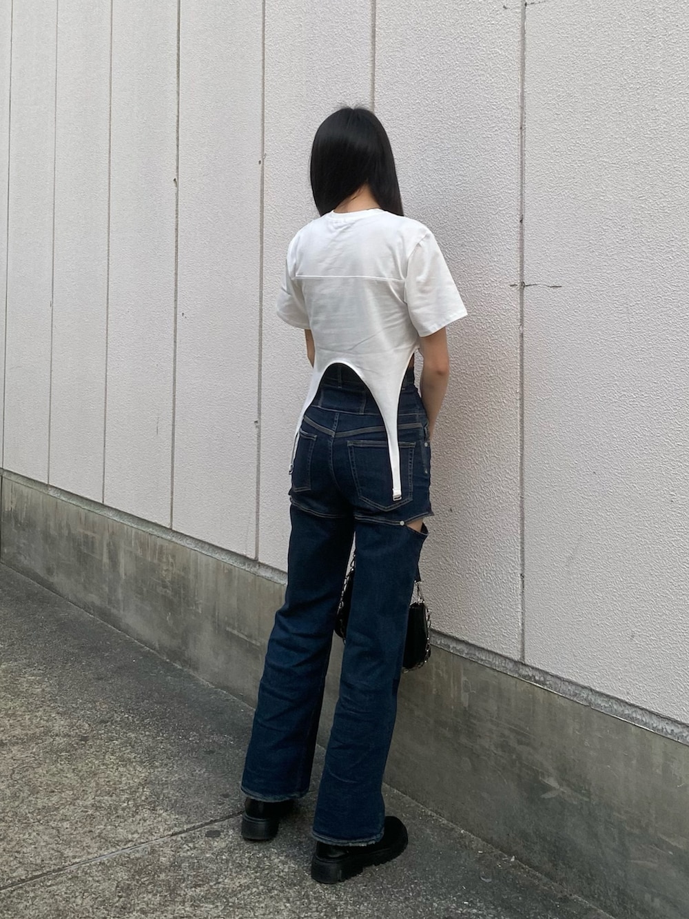 ブルー系のデニムパンツ、ブラック系のショルダーバッグ、ホワイト系のTシャツ/カットソーを着用したレディースの春コーディネートの3枚目の写真