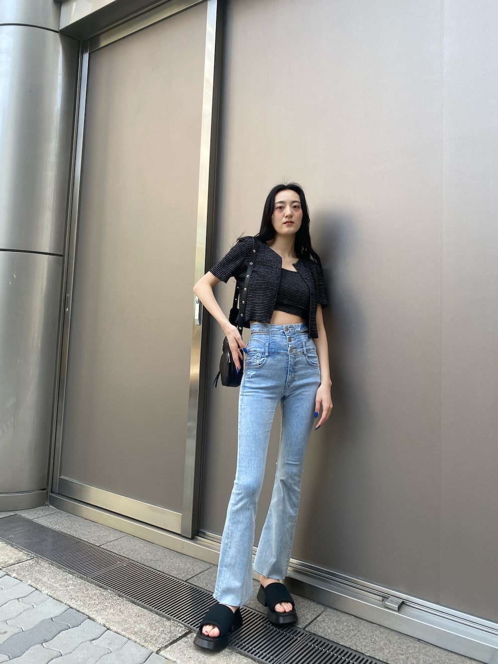 ブラック系のアンサンブル、ブルー系のデニムパンツ、ブラック系のサンダルを着用したレディースの春コーディネートの2枚目の写真