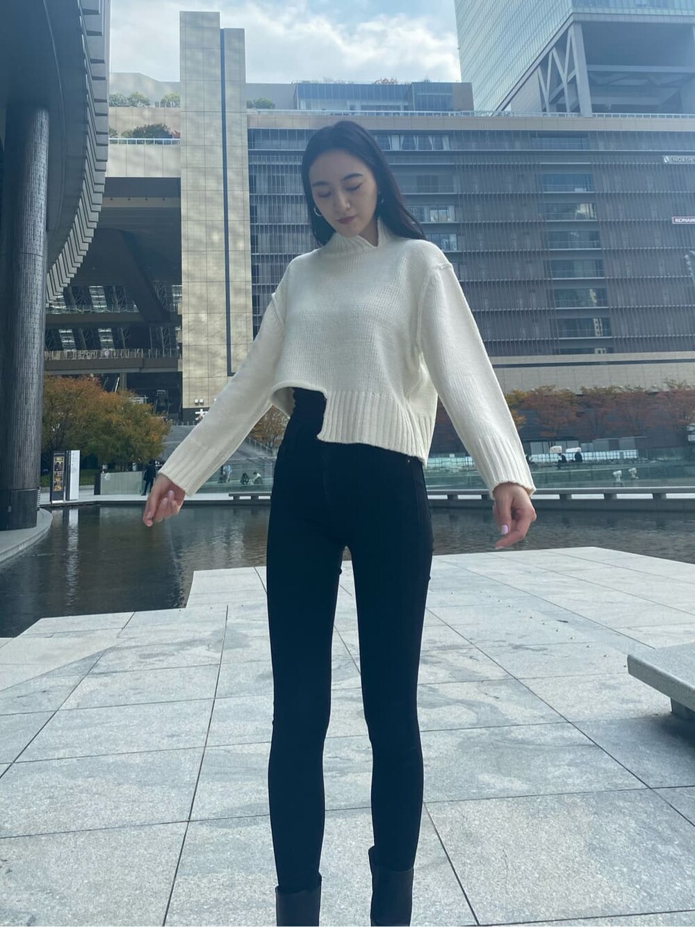 ブラック系のデニムパンツ、ホワイト系のニット/セーター、グリーン系のチェスターコートを着用したレディースの秋コーディネートの5枚目の写真