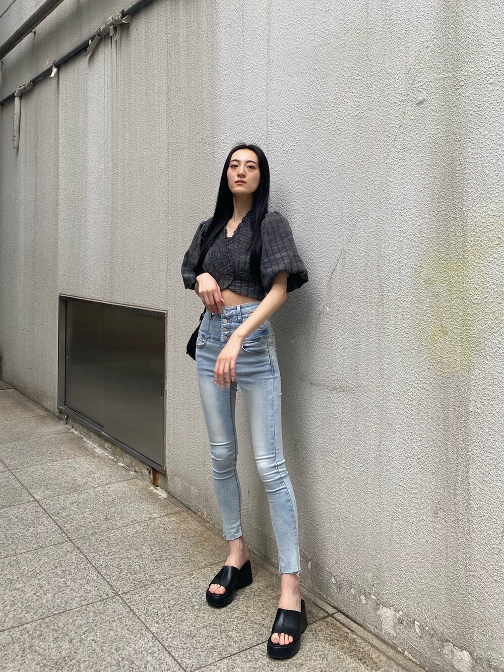 ブラック系のショルダーバッグ、ブラック系のTシャツ/カットソー、ブルー系のデニムパンツを着用したレディースの夏コーディネートの2枚目の写真