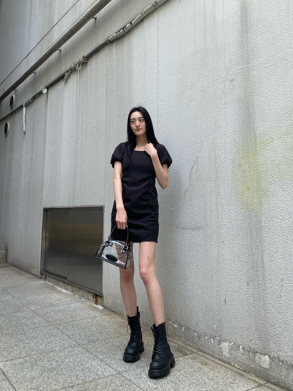 ブラック系のワンピース、ブラック系のブーツ、その他のハンドバッグを着用したレディースの春コーディネートの3枚目の写真