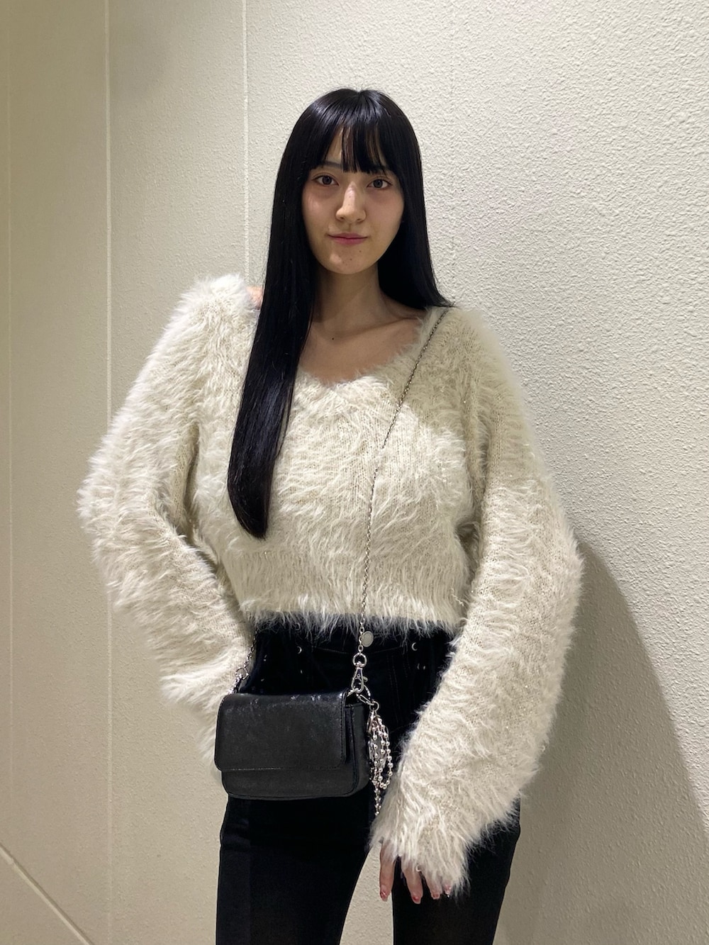 ホワイト系のニット/セーター、ブラック系のブーツ、ブラック系のデニムパンツを着用したレディースの冬コーディネートの6枚目の写真