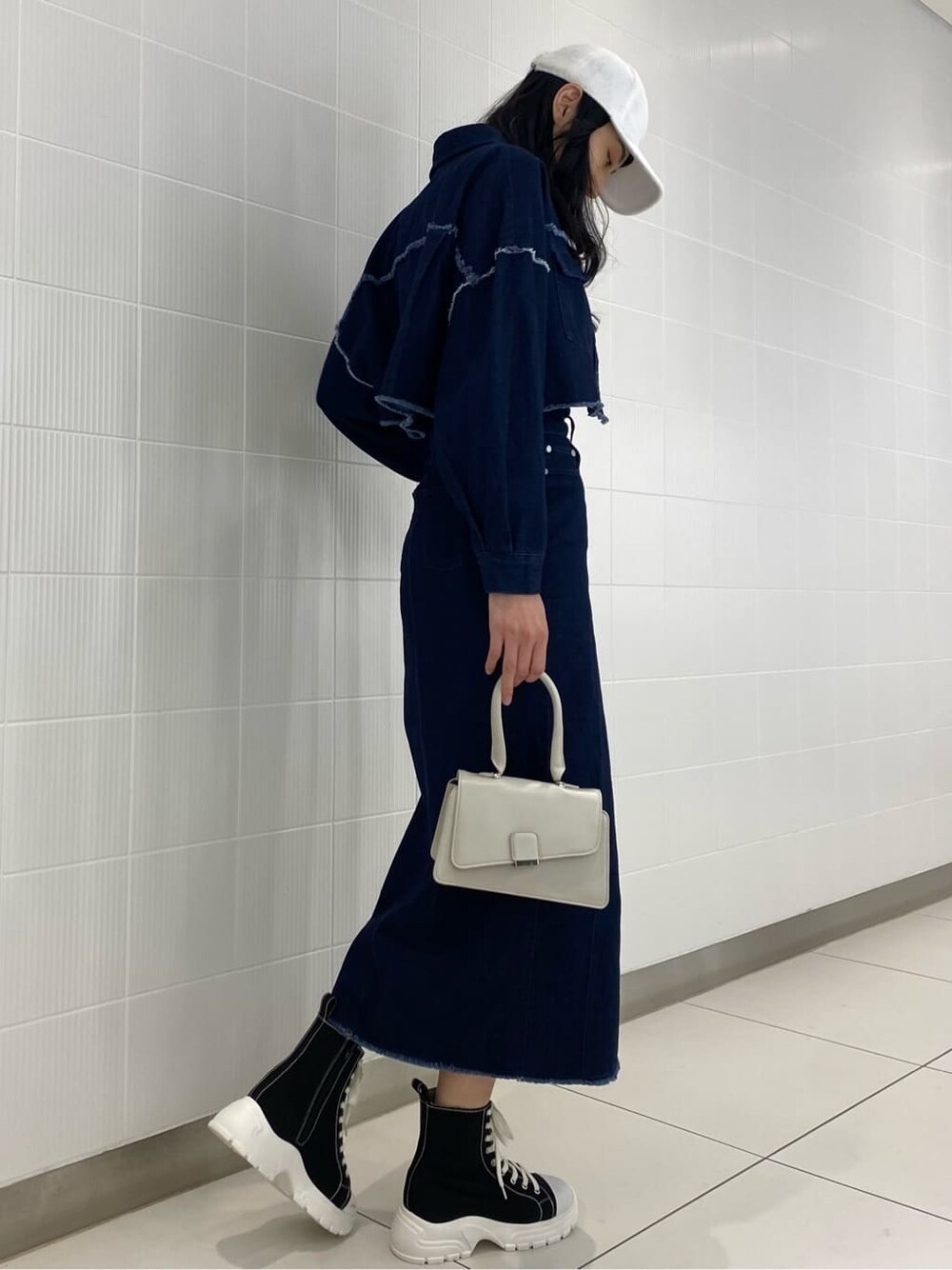 ブルー系のデニムジャケット、ブルー系のスカート、ホワイト系のハンドバッグを着用したレディースの夏コーディネートの2枚目の写真