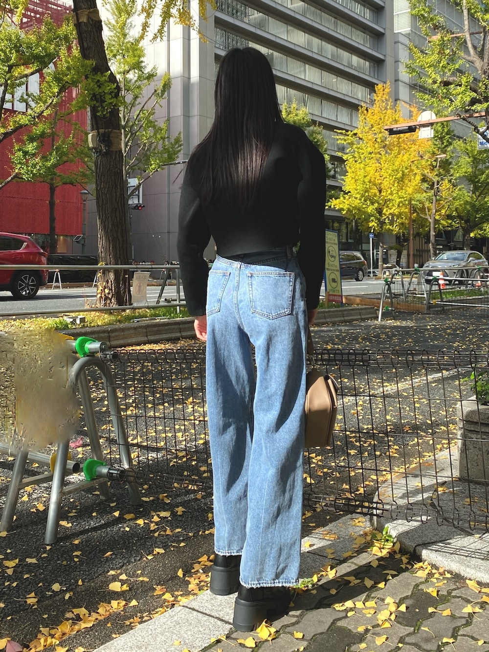 ブルー系のデニムパンツ、ブラック系のブーツ、ブラウン系のハンドバッグを着用したレディースの秋コーディネートの3枚目の写真