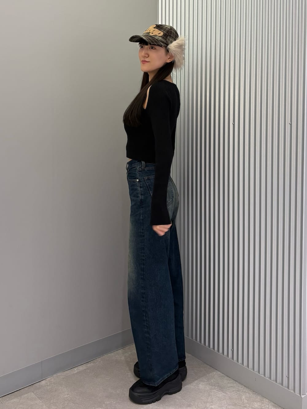 ブルー系のデニムパンツ、ブラック系のニット/セーター、ブラック系のスニーカーを着用したレディースの秋コーディネートの2枚目の写真