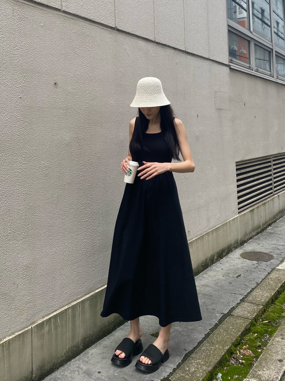 ブラック系のワンピース、ブラック系のサンダル、ホワイト系のハットを着用したレディースの夏コーディネートの2枚目の写真