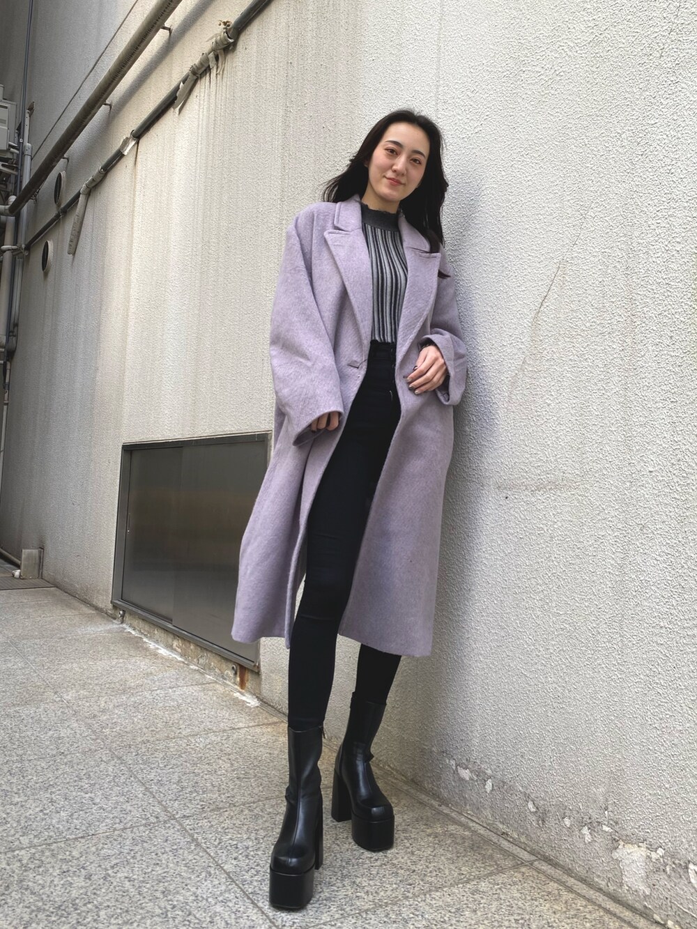 パープル系のチェスターコート、その他のニット/セーター、ブラック系のデニムパンツを着用したレディースの冬コーディネートの2枚目の写真