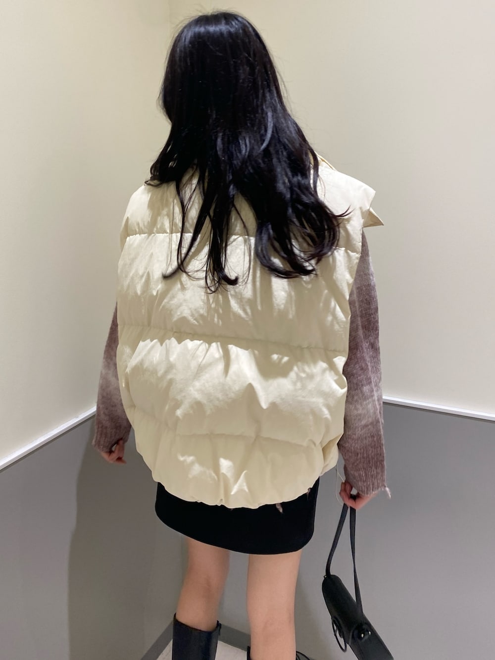 ブラック系のスカート、ピンク系のニット/セーター、ホワイト系のダウンベストを着用したレディースの秋コーディネートの5枚目の写真