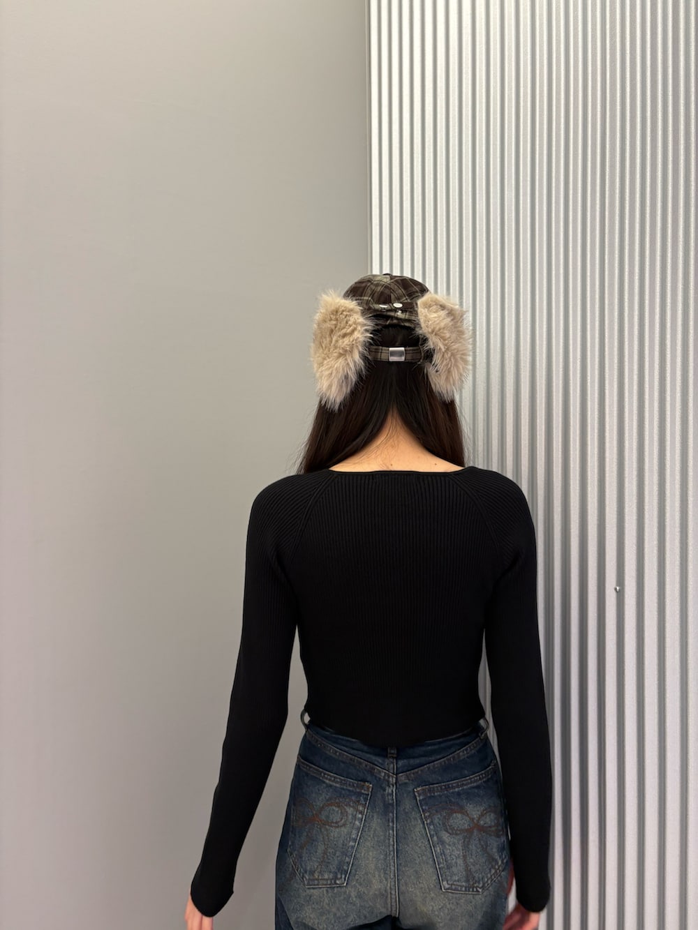 ブルー系のデニムパンツ、ブラック系のニット/セーター、ブラック系のスニーカーを着用したレディースの秋コーディネートの7枚目の写真