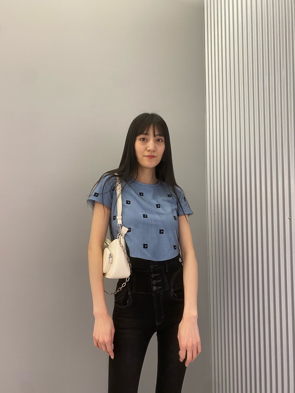 ブラック系のデニムパンツ、ブルー系のTシャツ/カットソー、ホワイト系のショルダーバッグを着用したレディースの春コーディネートの4枚目の写真